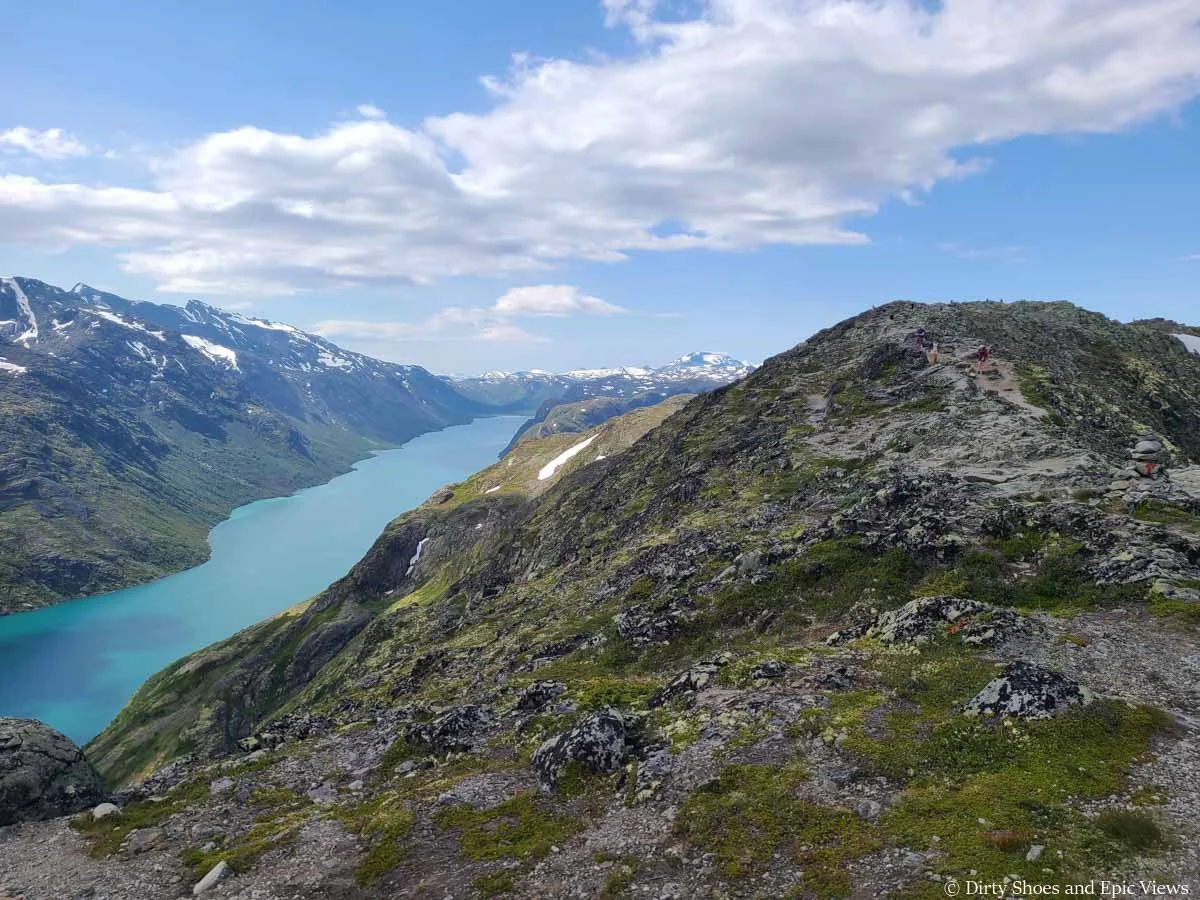 A rocky trail ascends gently above a blue lake on the Besseggen Ridge trail in Norway