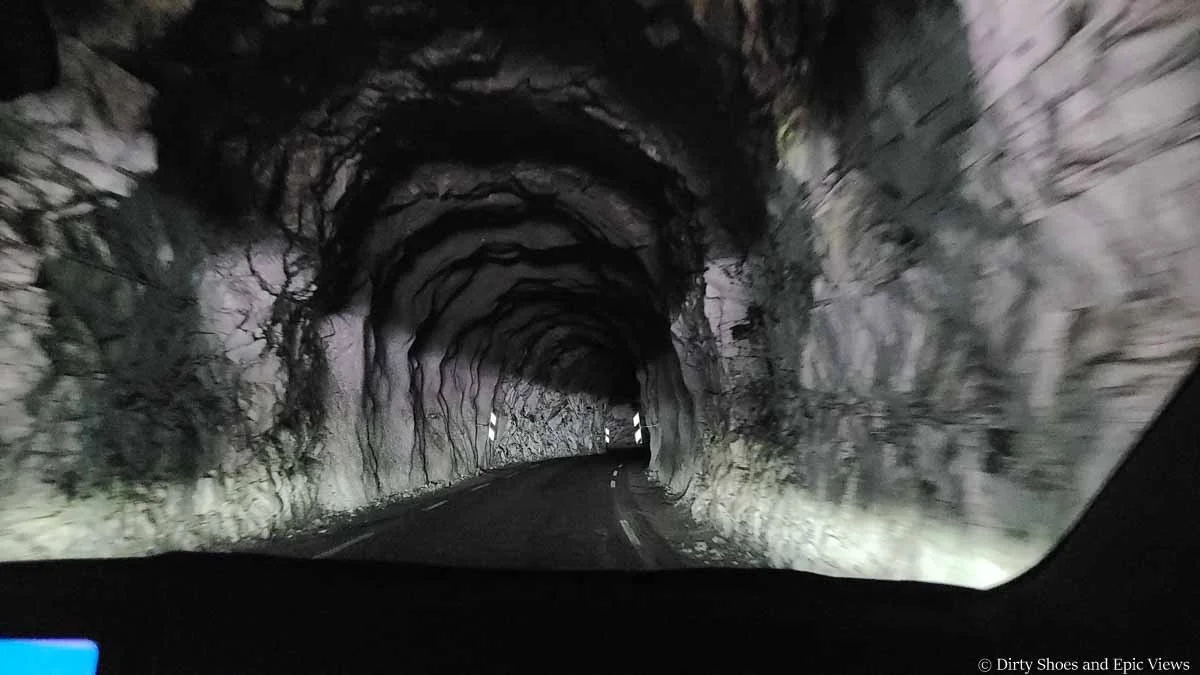 A car drives through a dark narrow rock tunnel on the way to Austerdalsbreen in Norway