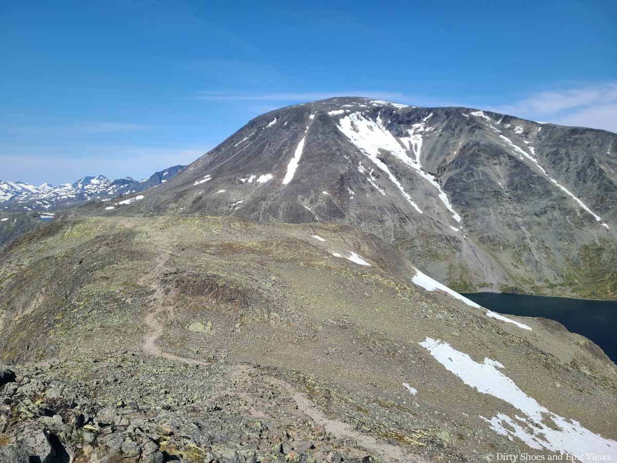A herd path traverses across a mountain plateau towards mountain views on the Besseggen Ridge Trail in Norway