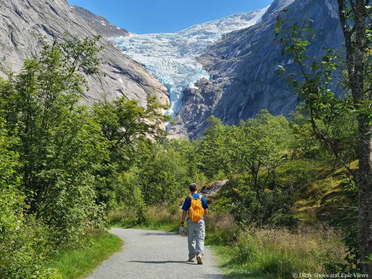 A hiker walks a flat path towards views of a giant glacier on the Briksdalsbreen hike in Norway