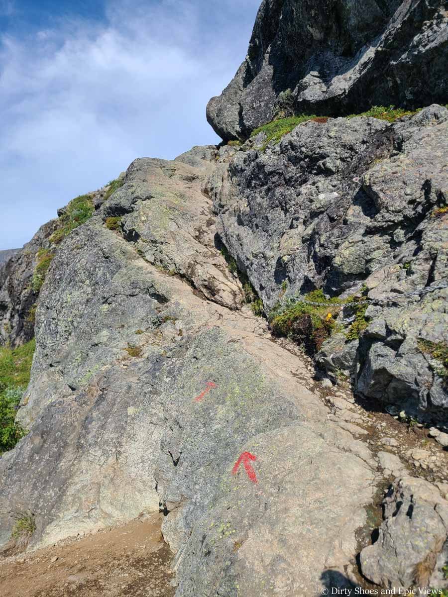 A chain runs along a narrow granite section of trail along the Bessegen Ridge hike in Norway