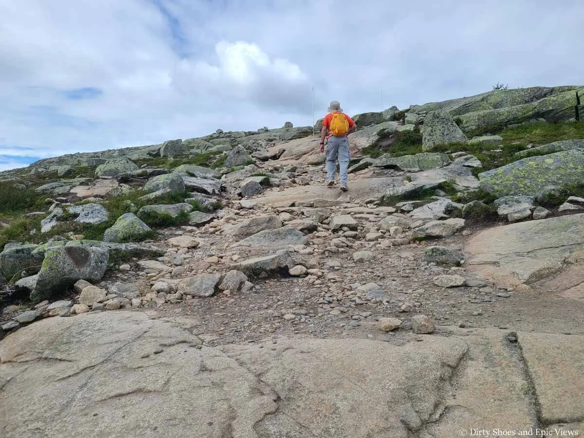 A hiker ascends a steep rocky trail on the Trolltunga hike