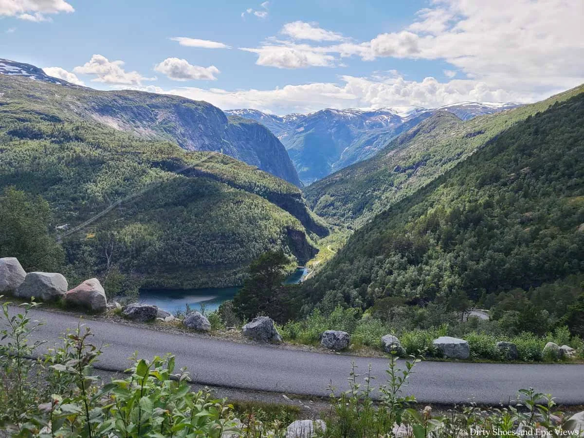 A view into a valley with a lake and distant snow-capped mountains from the Trolltunga hike in Norway