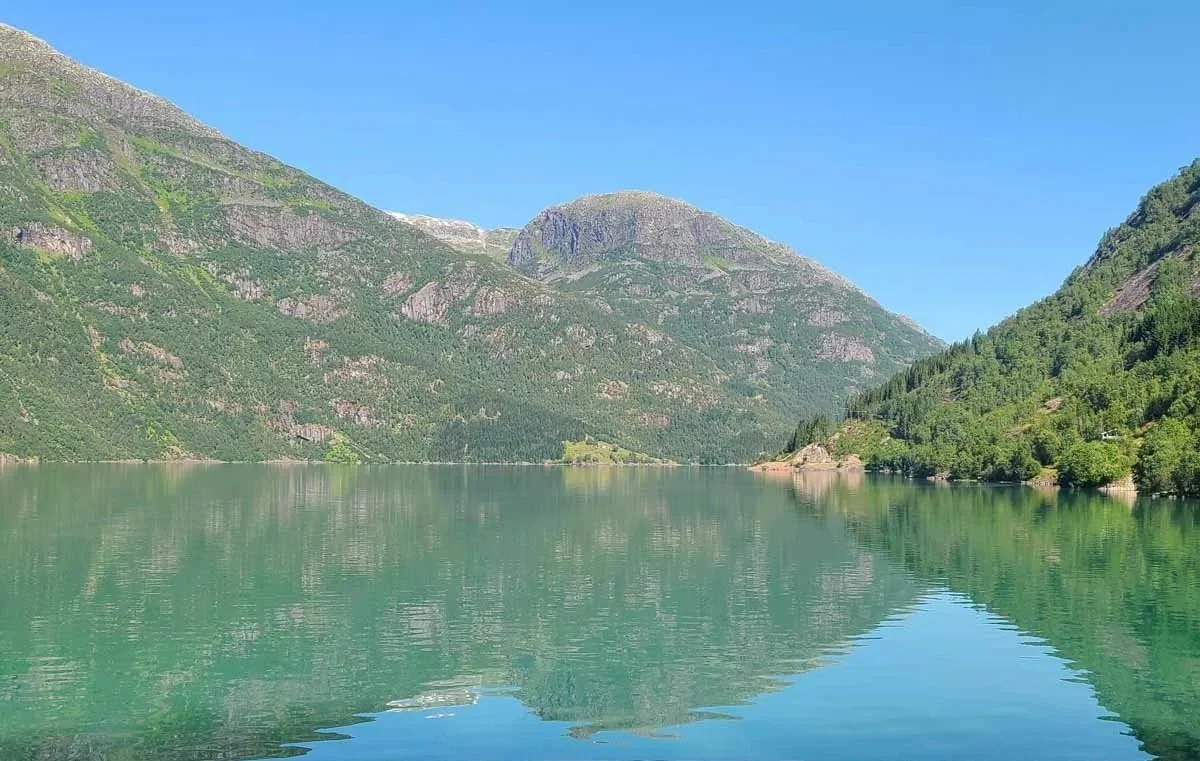 A blue lake reflects mountain views on the drive to Austerdalsbreen in Norway