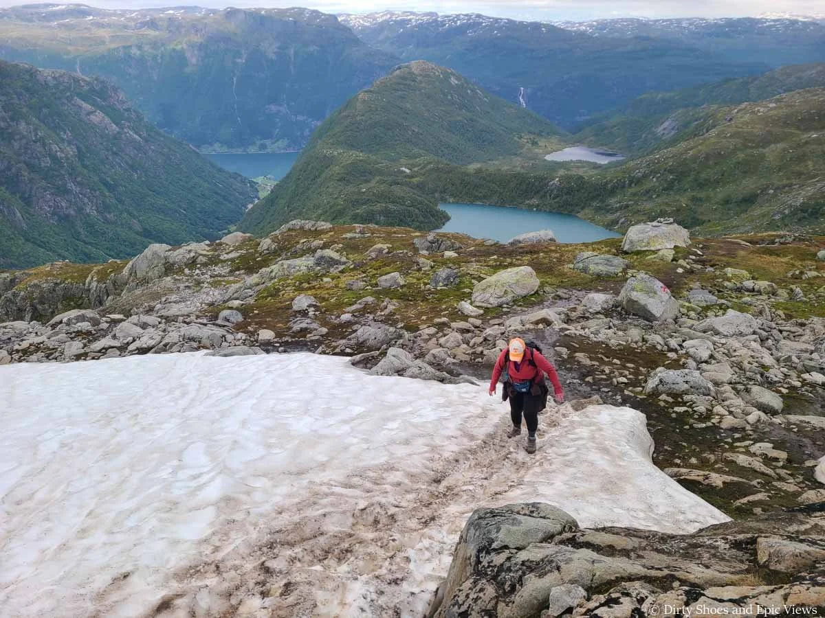 A hiker crosses a small snow patch on the Reinanuten trail in Norway