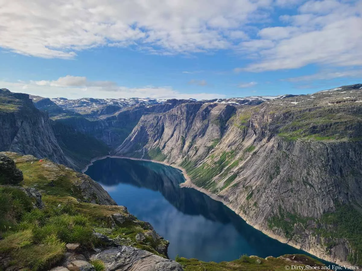 A deep blue lake sits beneath steep cliffs as seen from the Trolltunga hike