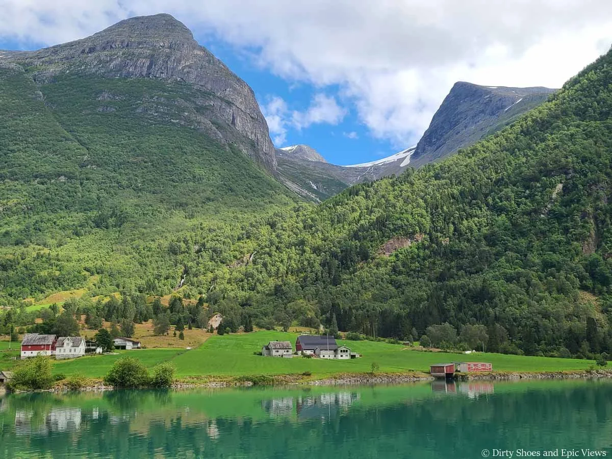 A quaint village sits beneath large rocky mountains near Briksdalsbreen in Norway