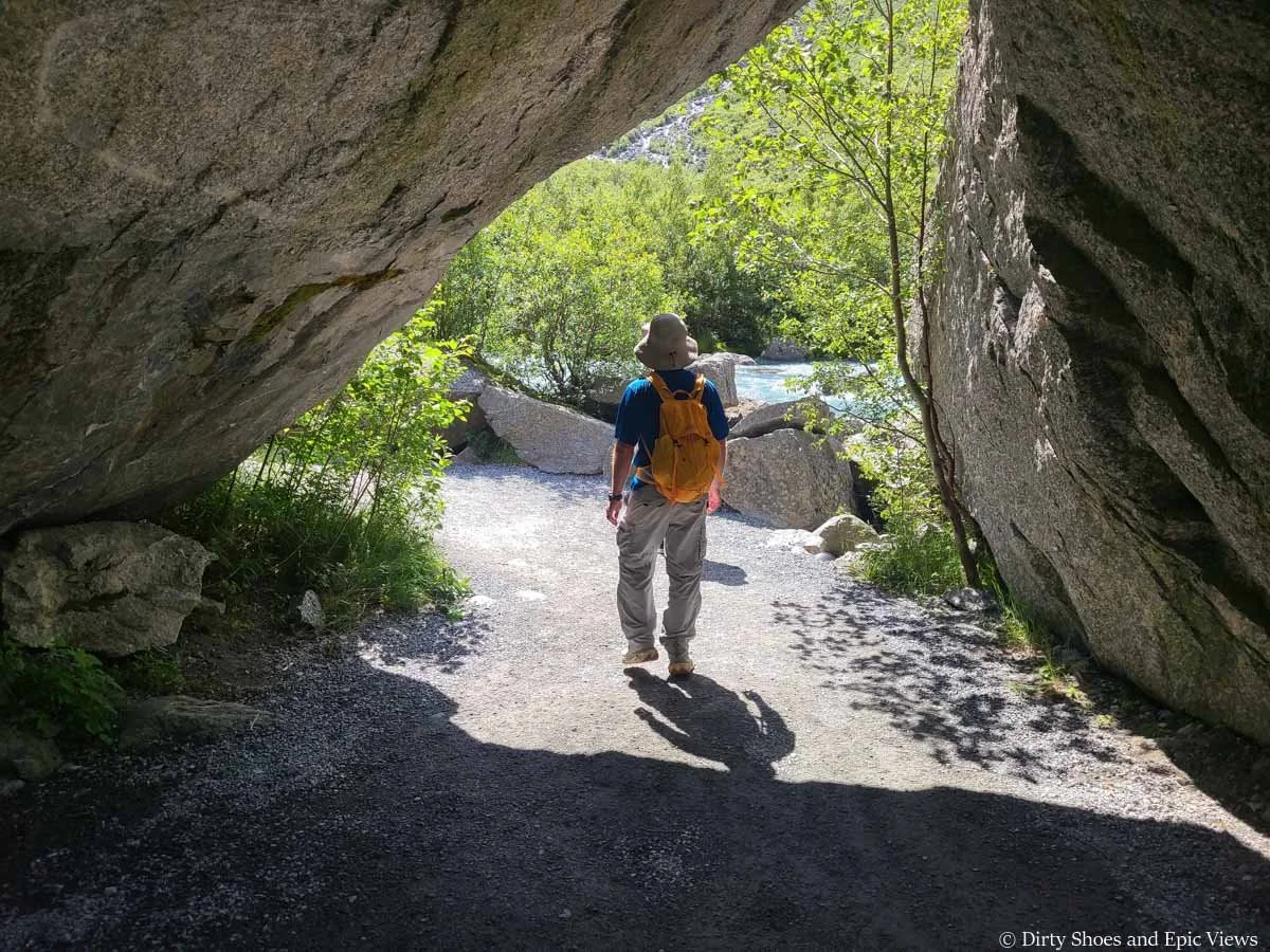 A hiker walks under a rock arch on the way to the Briksdal Glacier in Norway