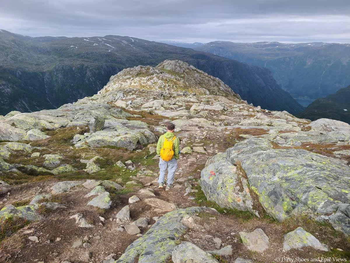 A hiker walks along a rocky ridge towards mountain views on the Reinanuten hike in Norway