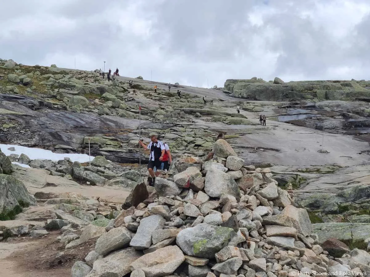Many hikers walk up and down a granite slab on the trail to Trolltunga