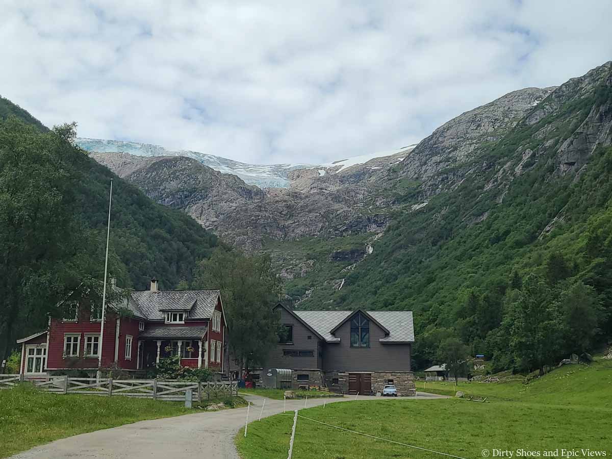 Two houses sit beneath glacier-capped cliffs at the Reinanuten trailhead