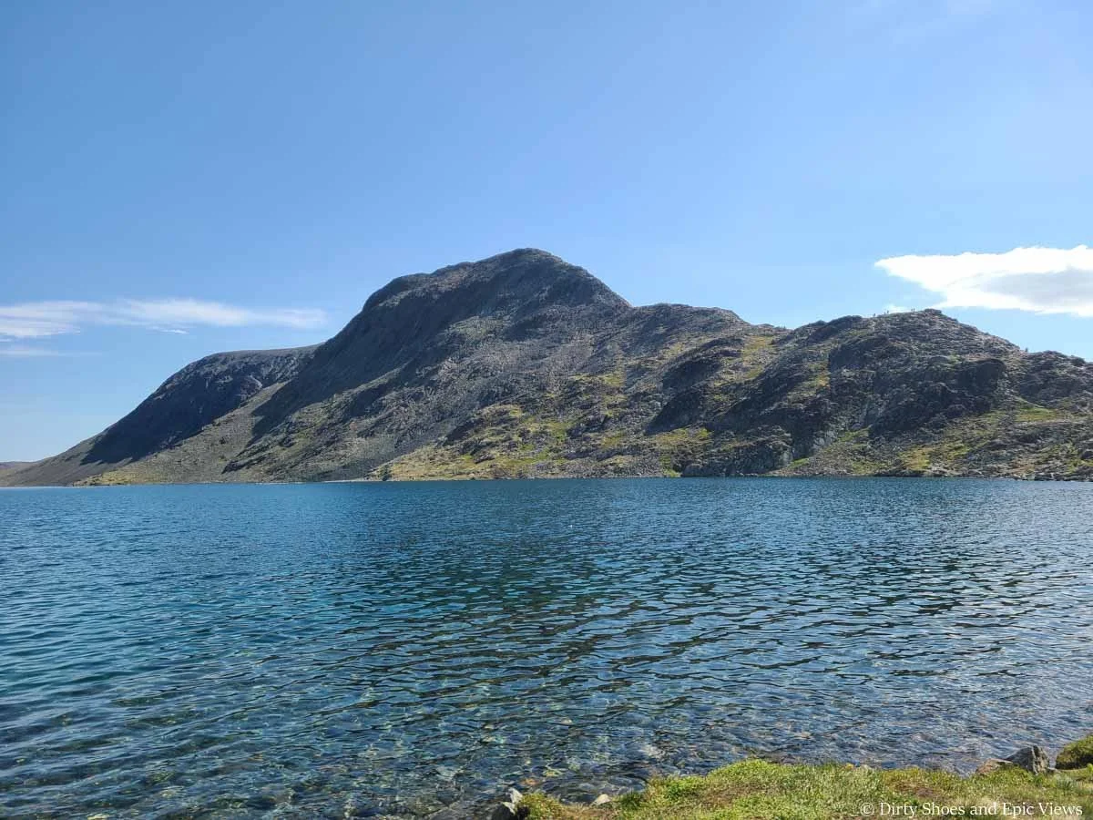 A rocky ridge sits above a clear blue lake along the Besseggen Ridge hike in Norway