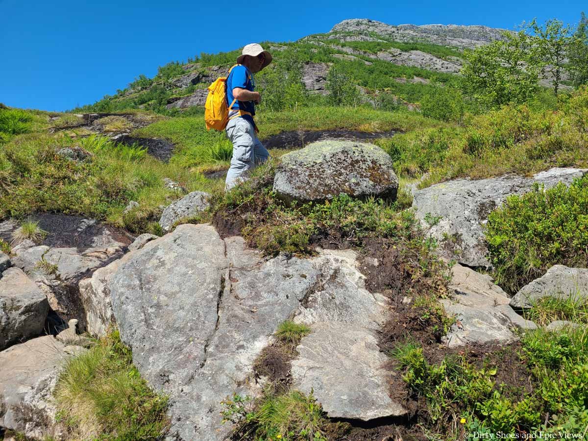 A hiker navigates rocky and muddy terrain on the Austerdalsbreen trail