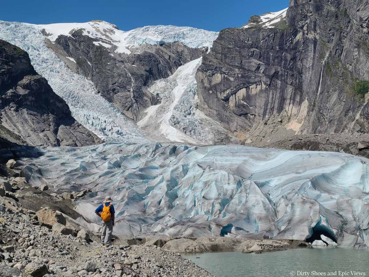 A hiker stands at the base of a giant glacier on the Austerdalsbreen hike in Norway