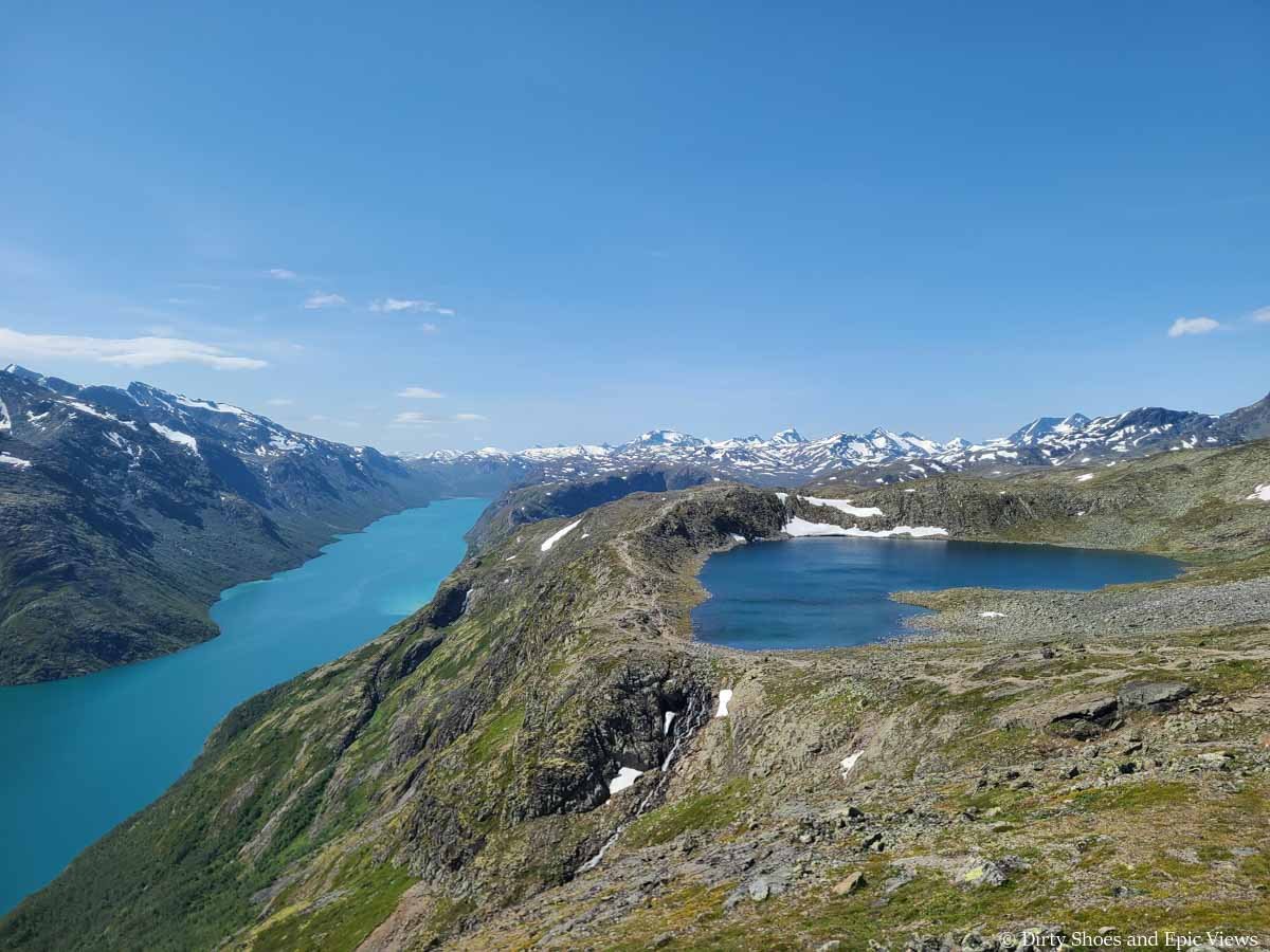 Two blue lakes sit in front of snowy mountains on the  Besseggen Ridge trail in Norway