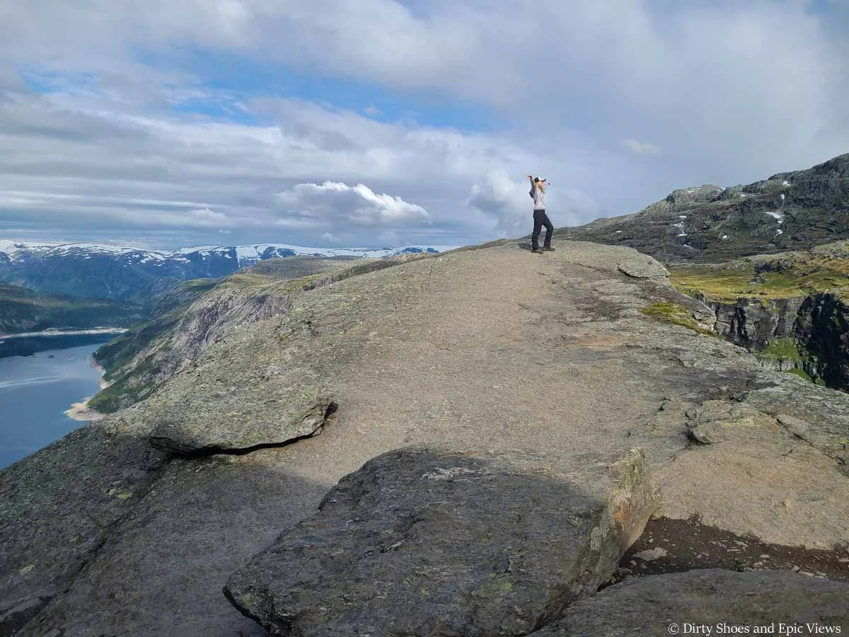 A woman poses on a rocky outcropping above a lake at Trolltunga