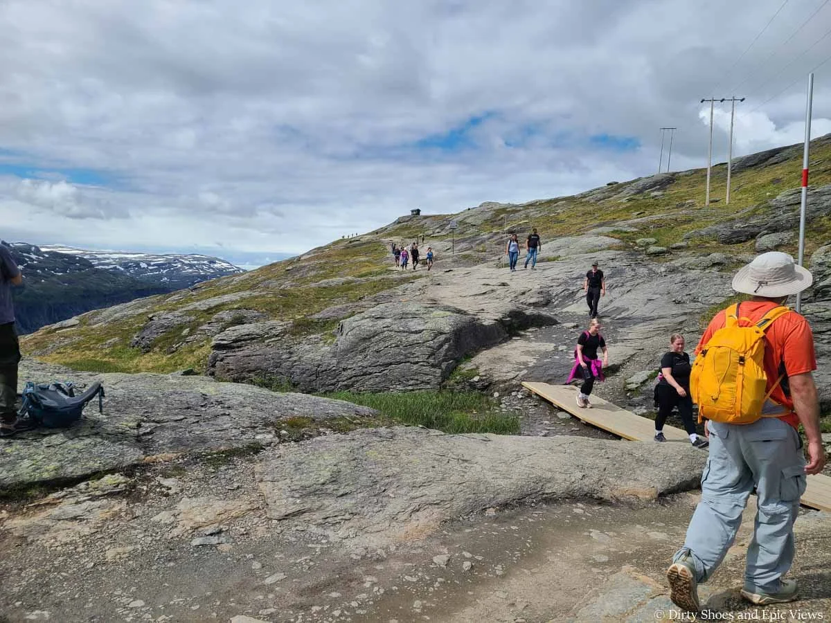 A line of hikers walk along a rocky path on the Trolltunga trail
