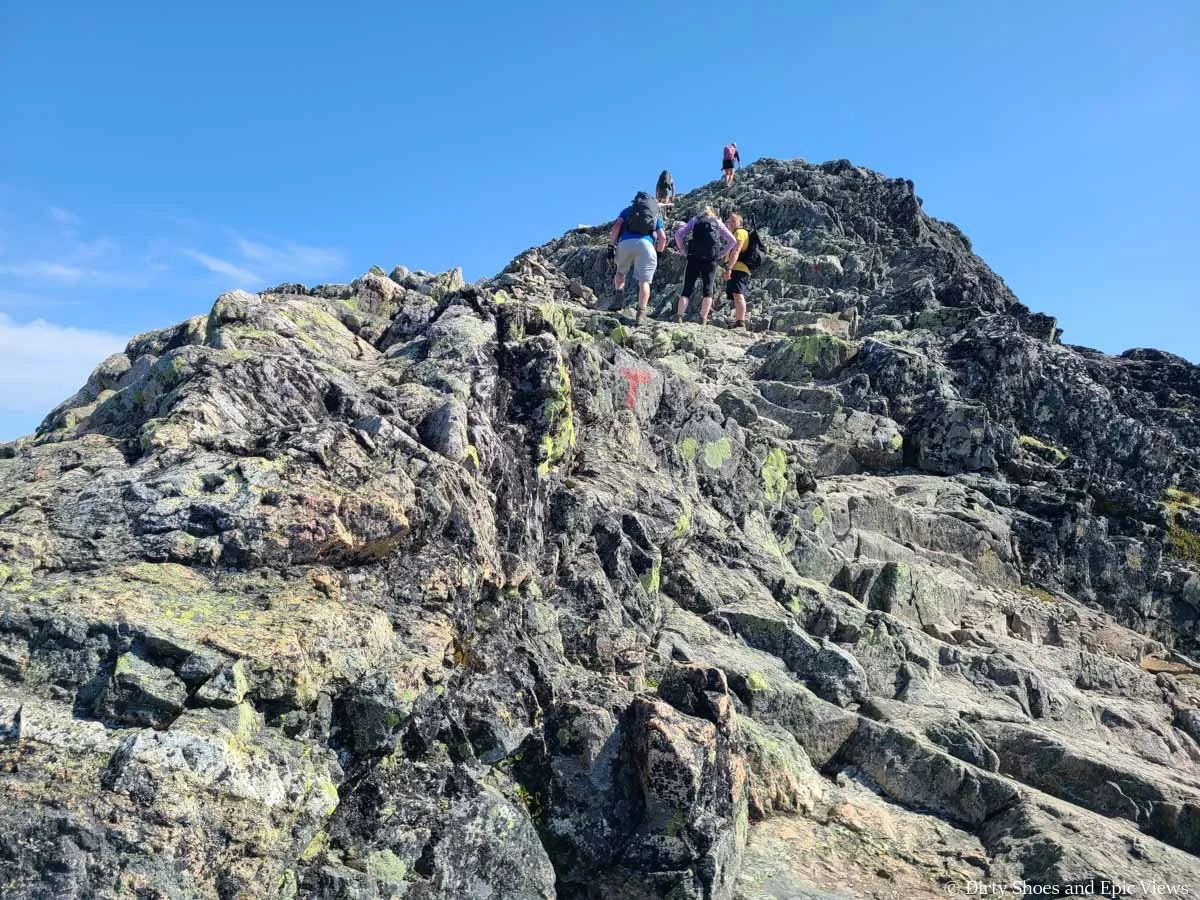 Hikers scramble up a steep rocky ascent on the Besseggen Ridge trail in Norway