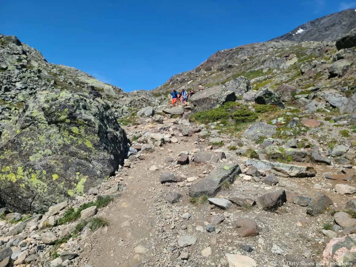 Hikers descend down a rocky and dirt path along Besseggen Ridge in Norway