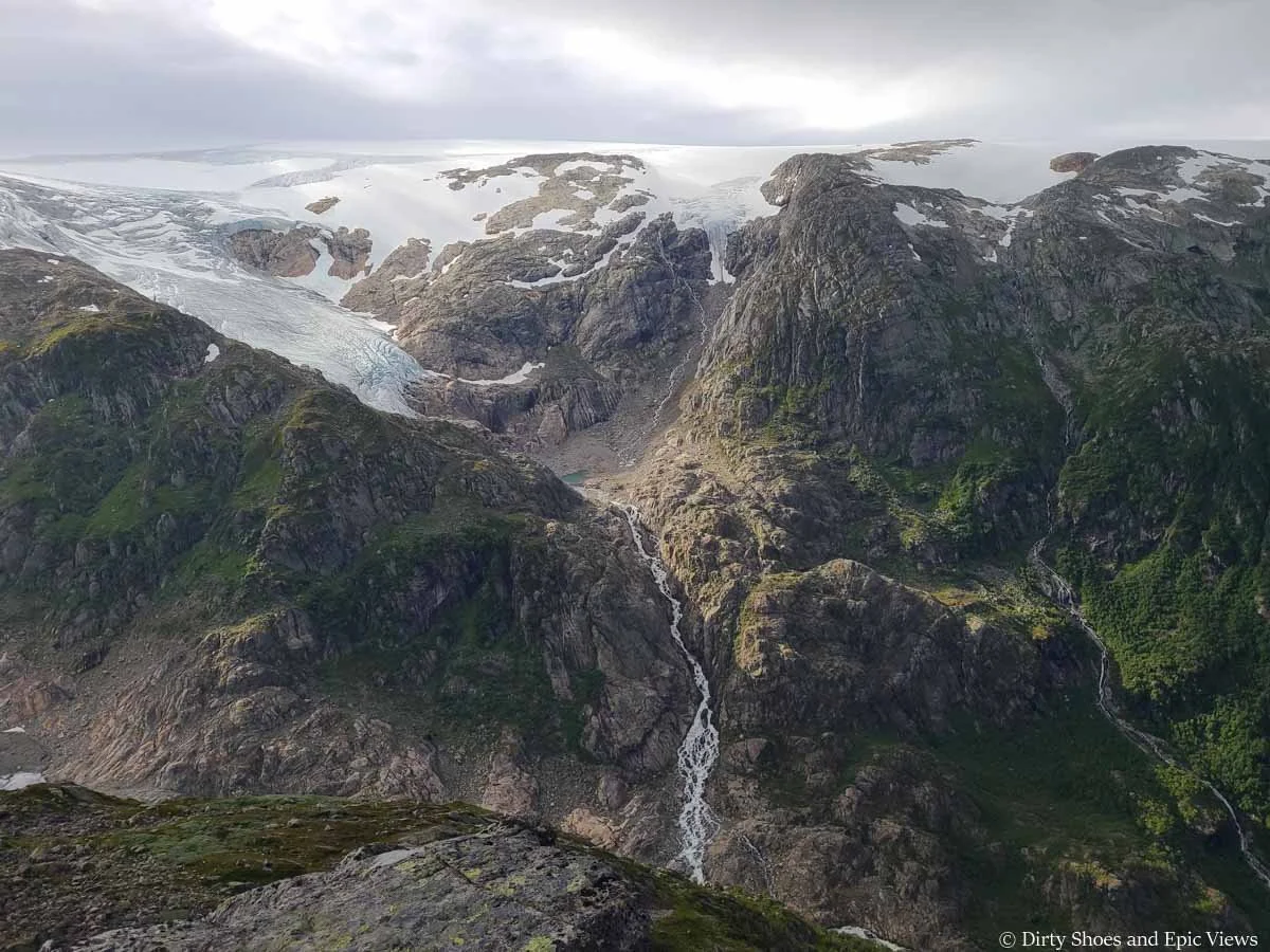 Waterfalls cascade down a cliffside below an icecap as seen from the Reinanuten hike in Norway