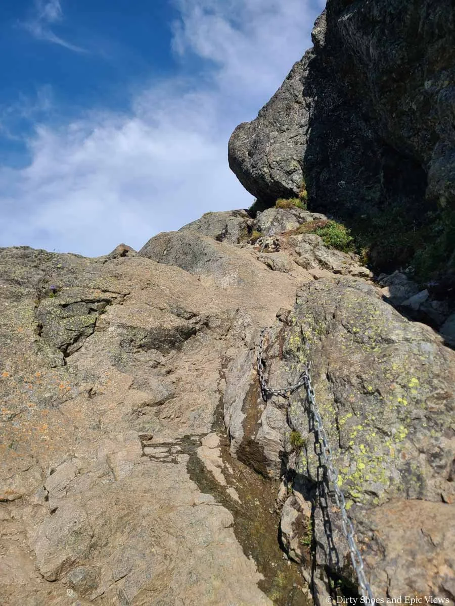 A chain runs along a steep and wet granite rock along the Besseggen Ridge trail in Norway