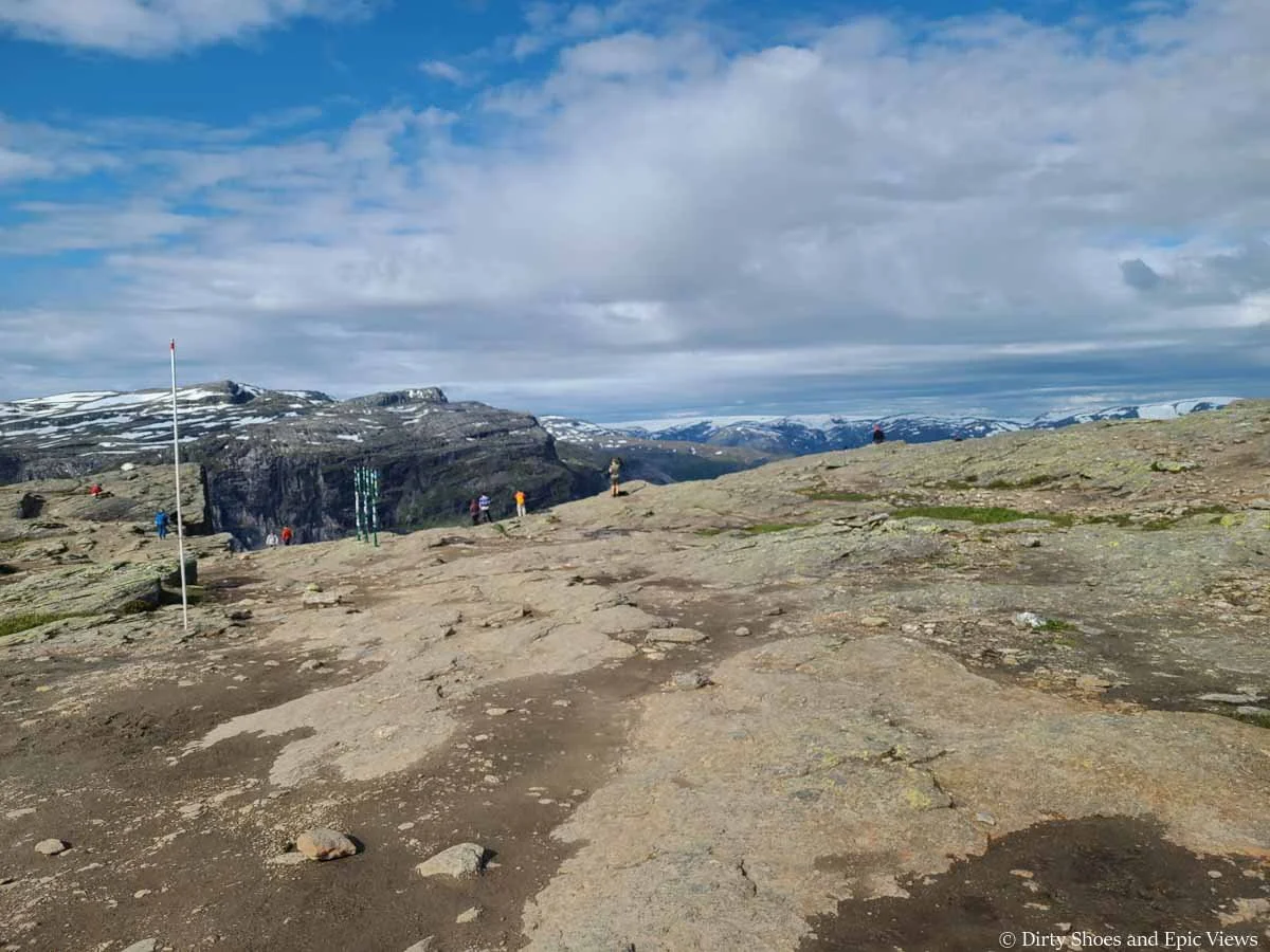 People stand at the edge of a cliff overlooking mountain views at Trolltunga in Norway