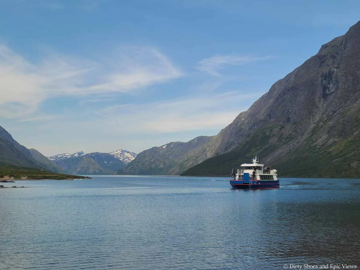 A small ferry crosses a scenic lake with mountain views for the Besseggen Ridge hike