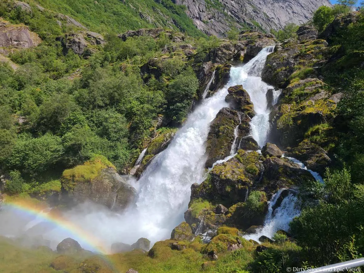 A rainbow sits in front of a powerful waterfall along the Briksdal Glacier trail in Norway