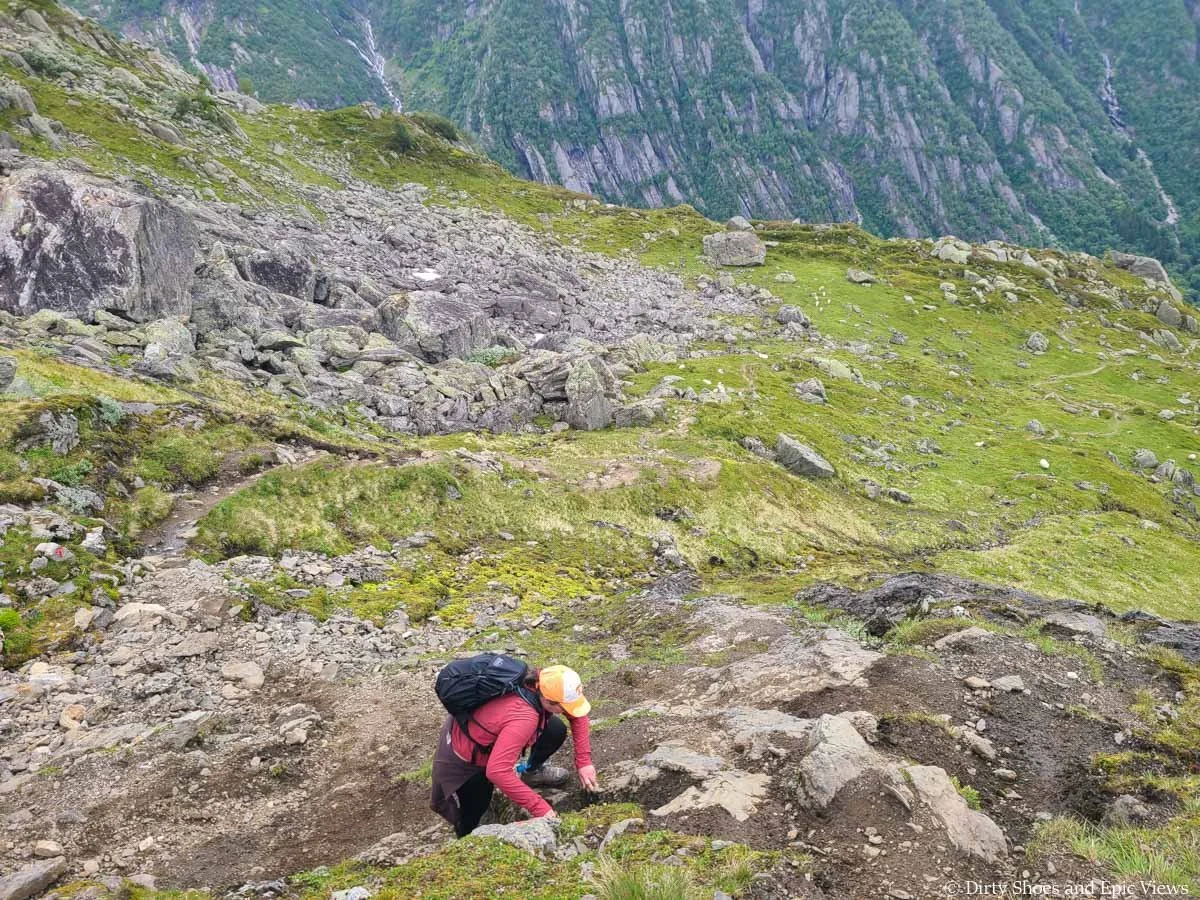 A hiker makes a quick scramble up a tricky rocky part of the Reinanuten trail in Norway
