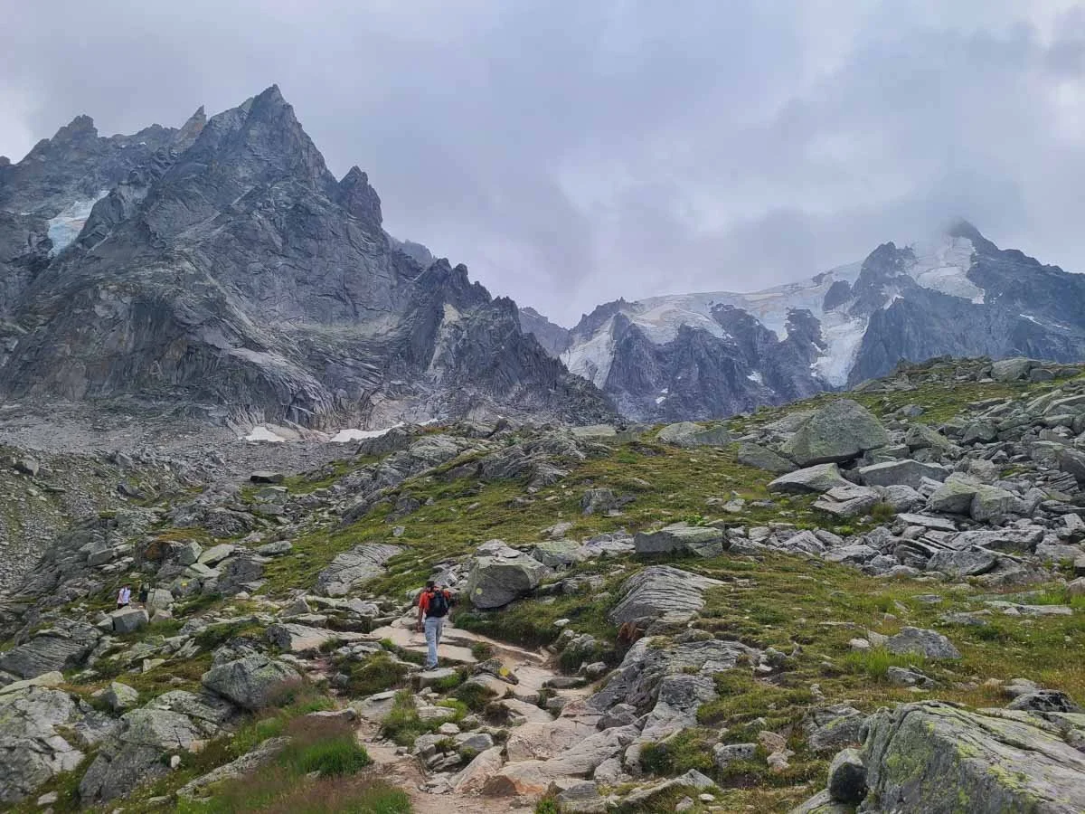 A hiker walks a rocky path with alpine views on the trail to Lac Bleu in Chamonix