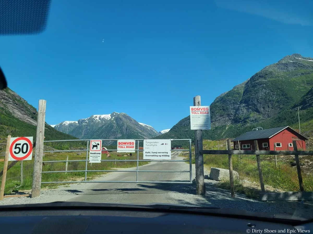 A toll gate crosses a gravel road on the way towards mountain views on the drive to Austerdalsbreen in Norway