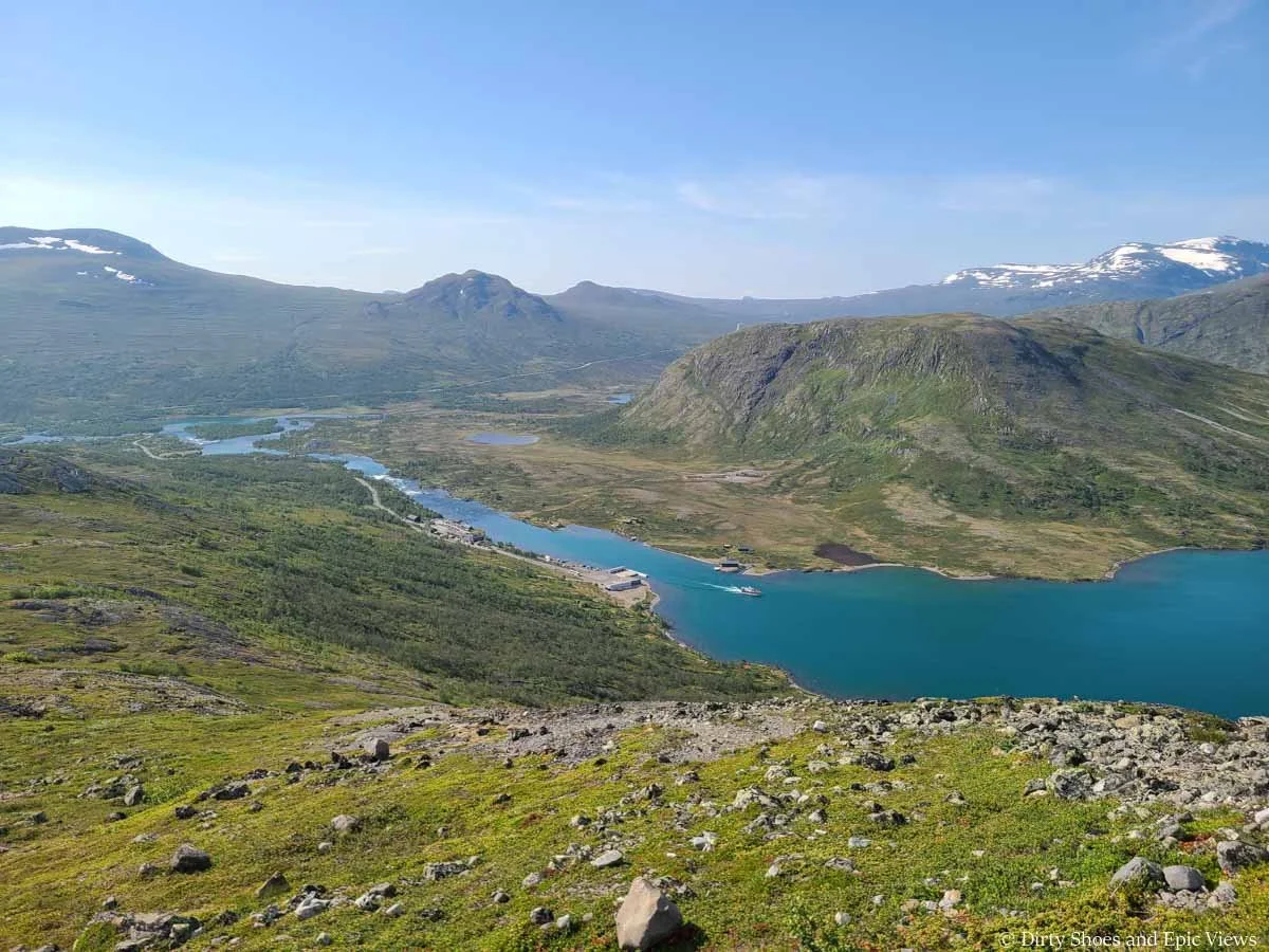 Views over a blue lake surrounded by green hills and mountains from the Besseggen Ridge trail in Norway