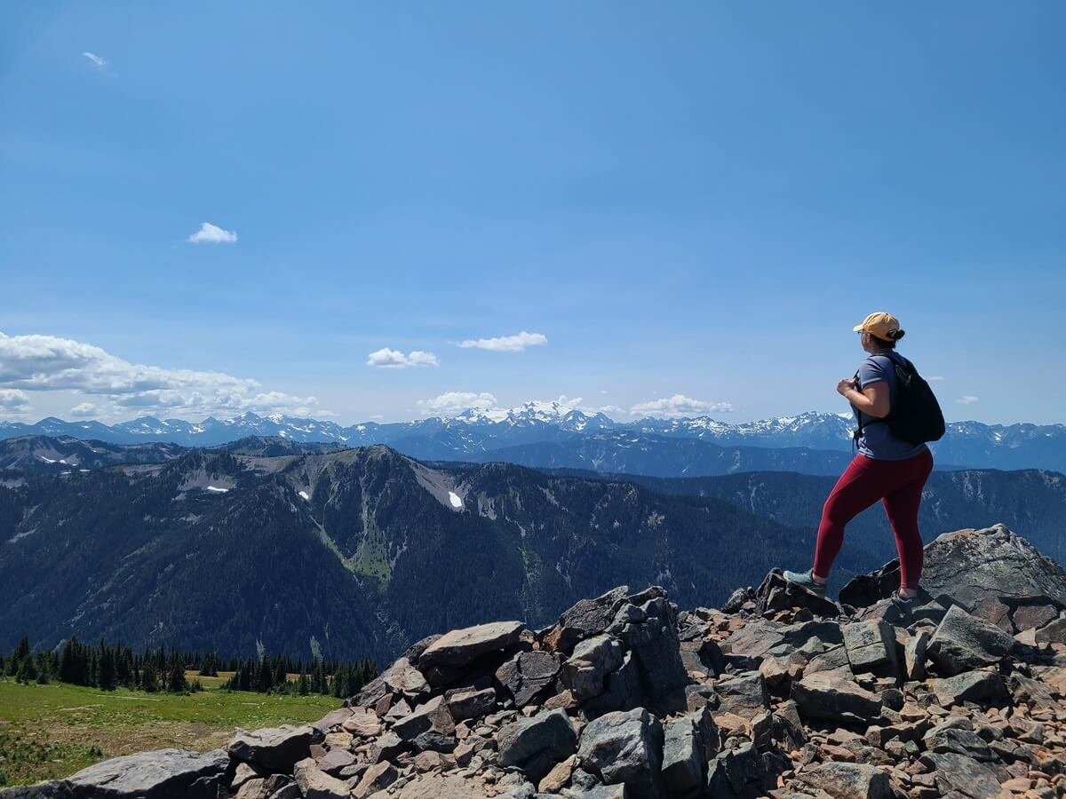 A hiker stands atop a viewpoint overlooking the Olympic Range near Obstruction Point