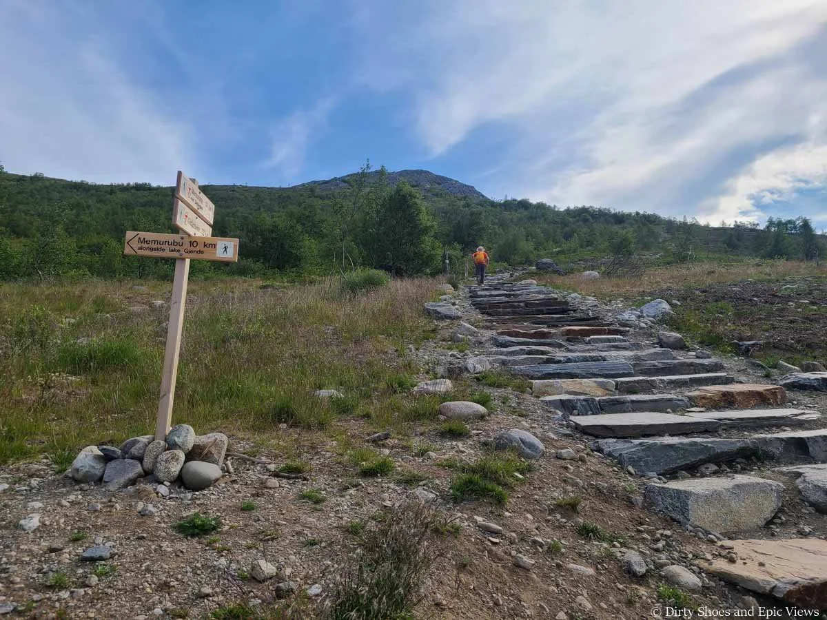 A hiker climbs a series of stone steps at the start of the Besseggen Ridge hike in Norway