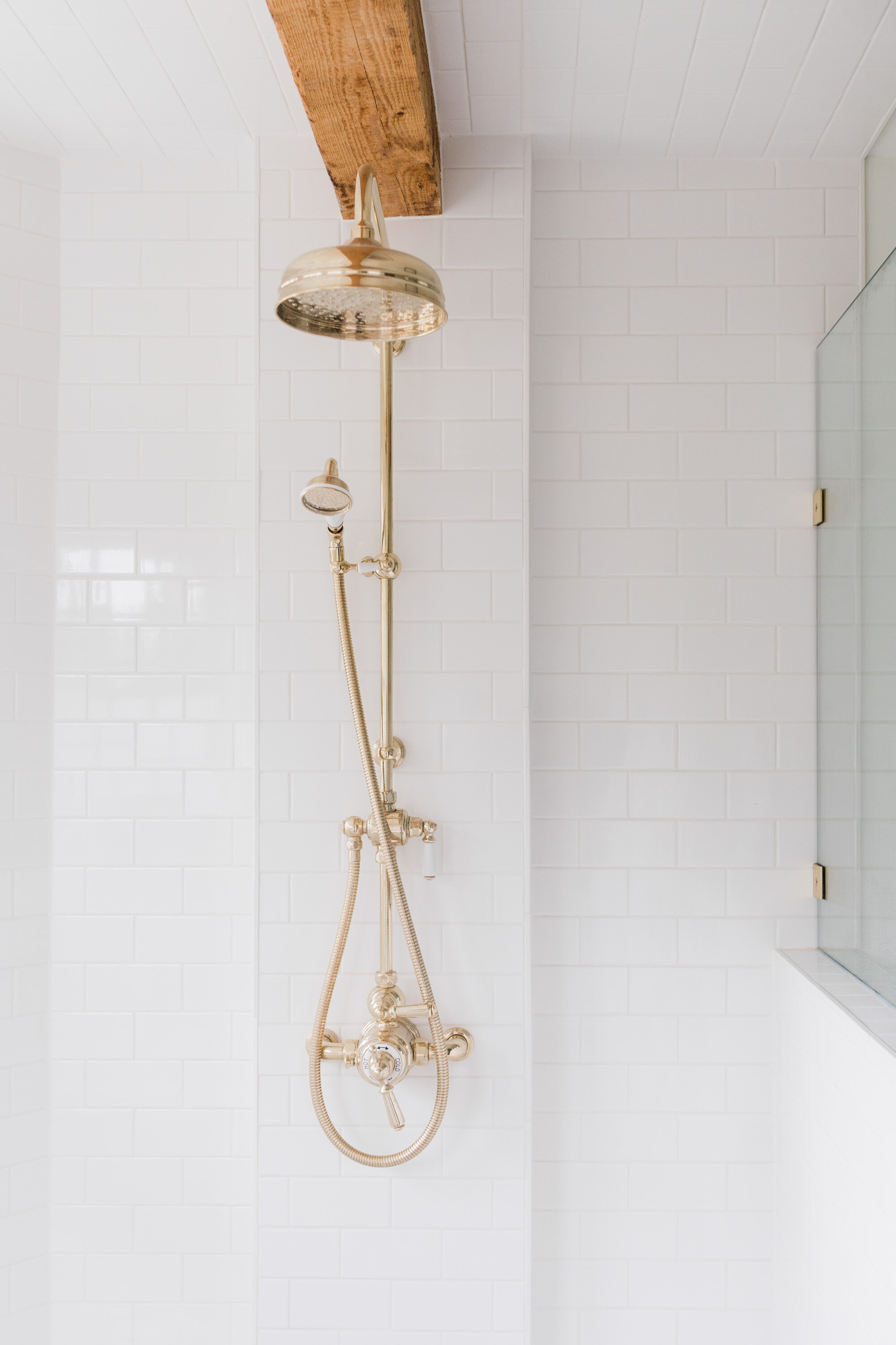 white shower tile with brass fixtures
