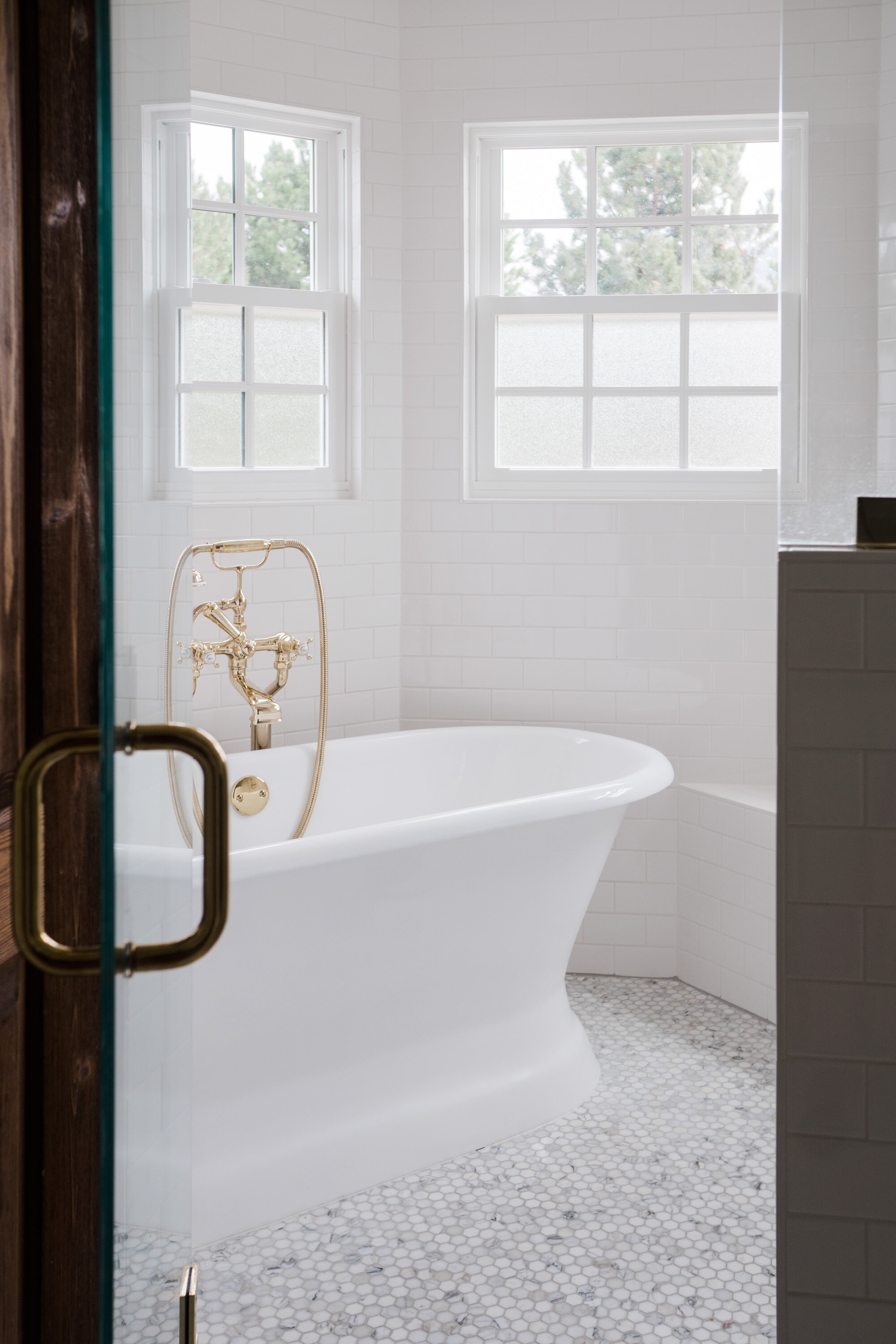 White bathtub with brass fixtures and white tiles