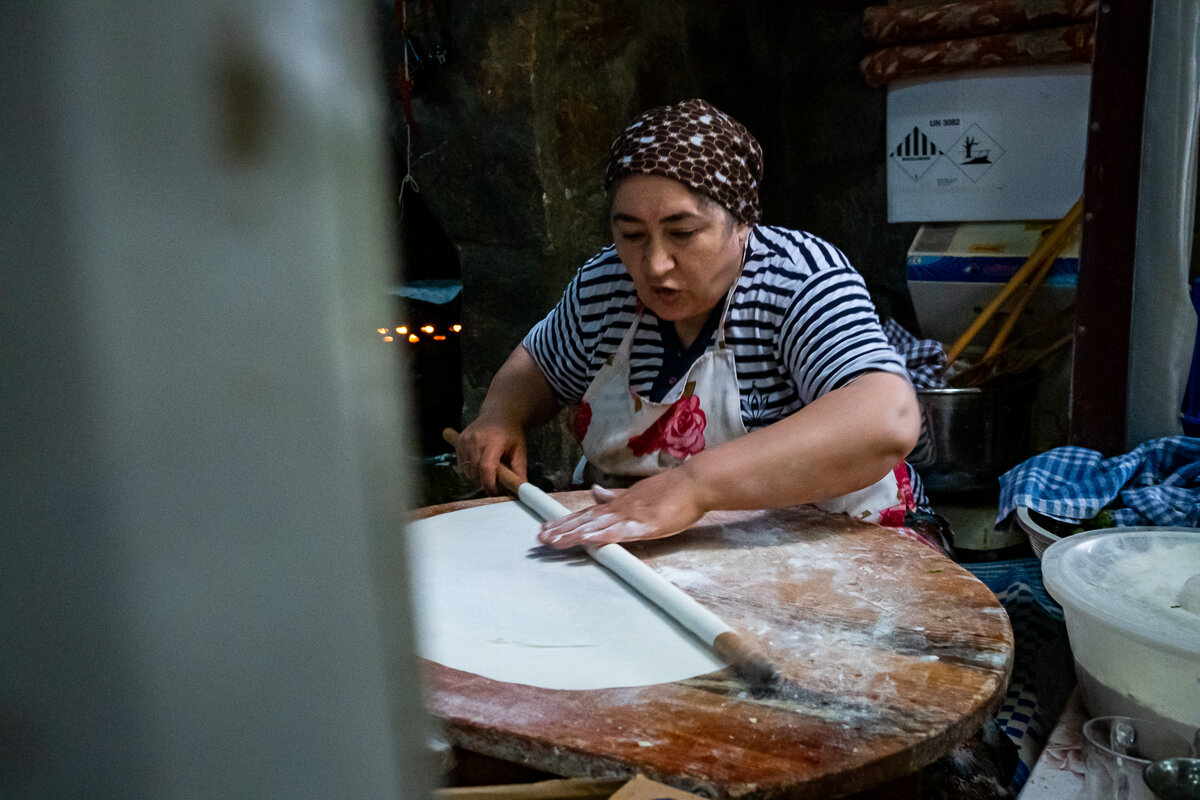 A cook prepares Gozleme, a popular and delicious snack consisting of pastry dough, cheese, and spinach, all prepared on the spot and cooked over a hot stone oven.