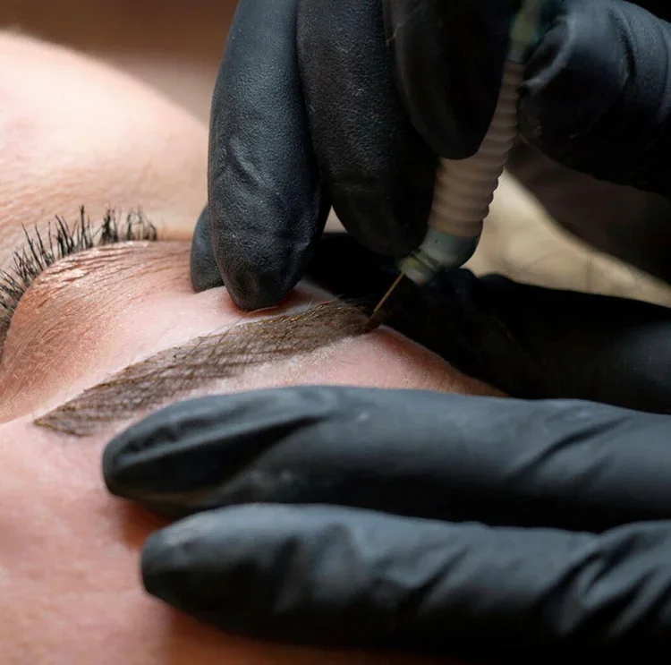 Student practicing microblading technique on a live model during PMU training