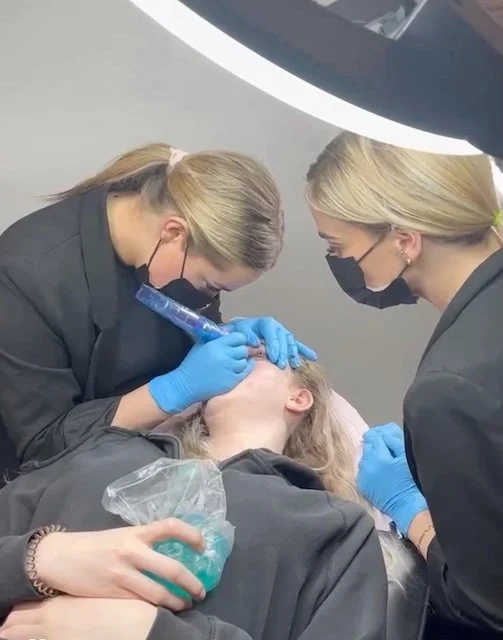 Brittany training a permanent makeup artist during an eyeliner procedure at The Beauty Block in Calgary.