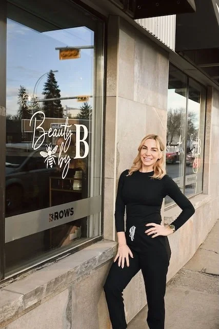 Brittany standing beside Beauty by B window signage with honey bee logo