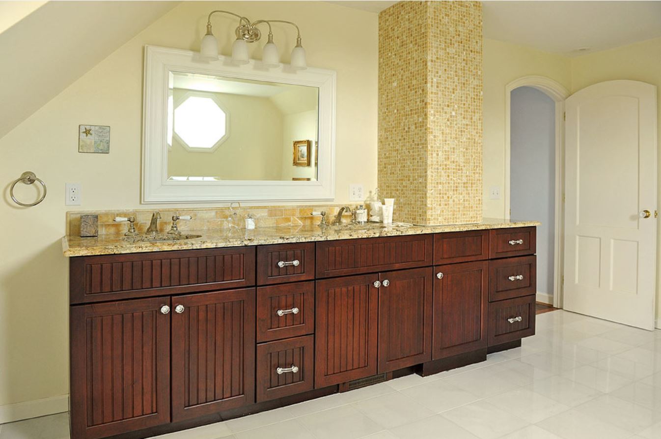 Bathroom vanity with dark wood cabinets and gold tile