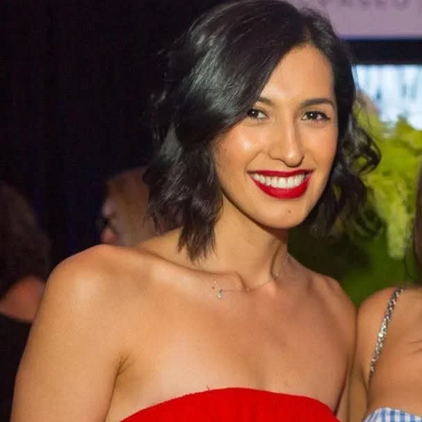 Woman with shoulder length black hair wearing a strapless red top and red lipstick