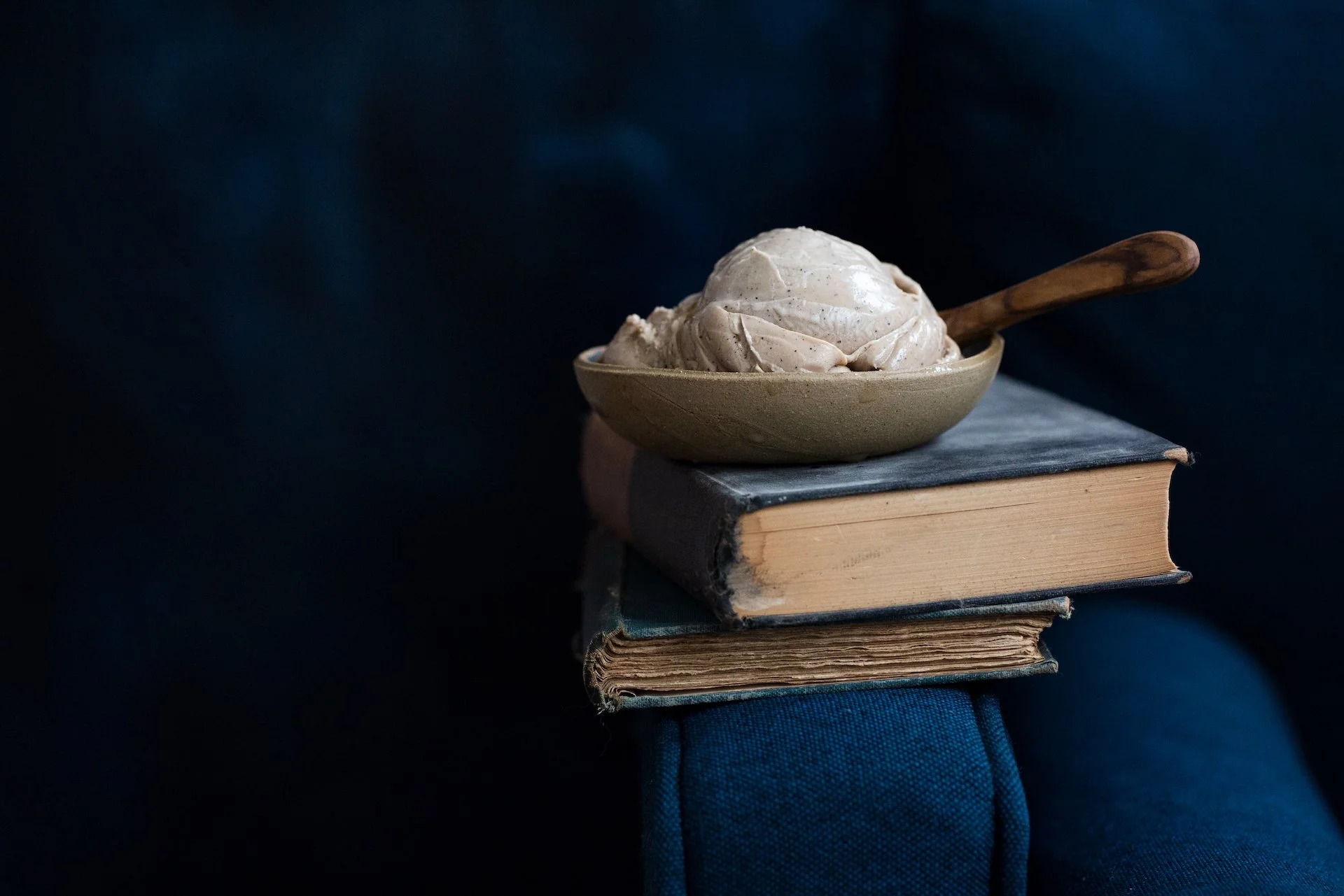 Bowl of ice cream sitting on a blue-covered book, with a black background