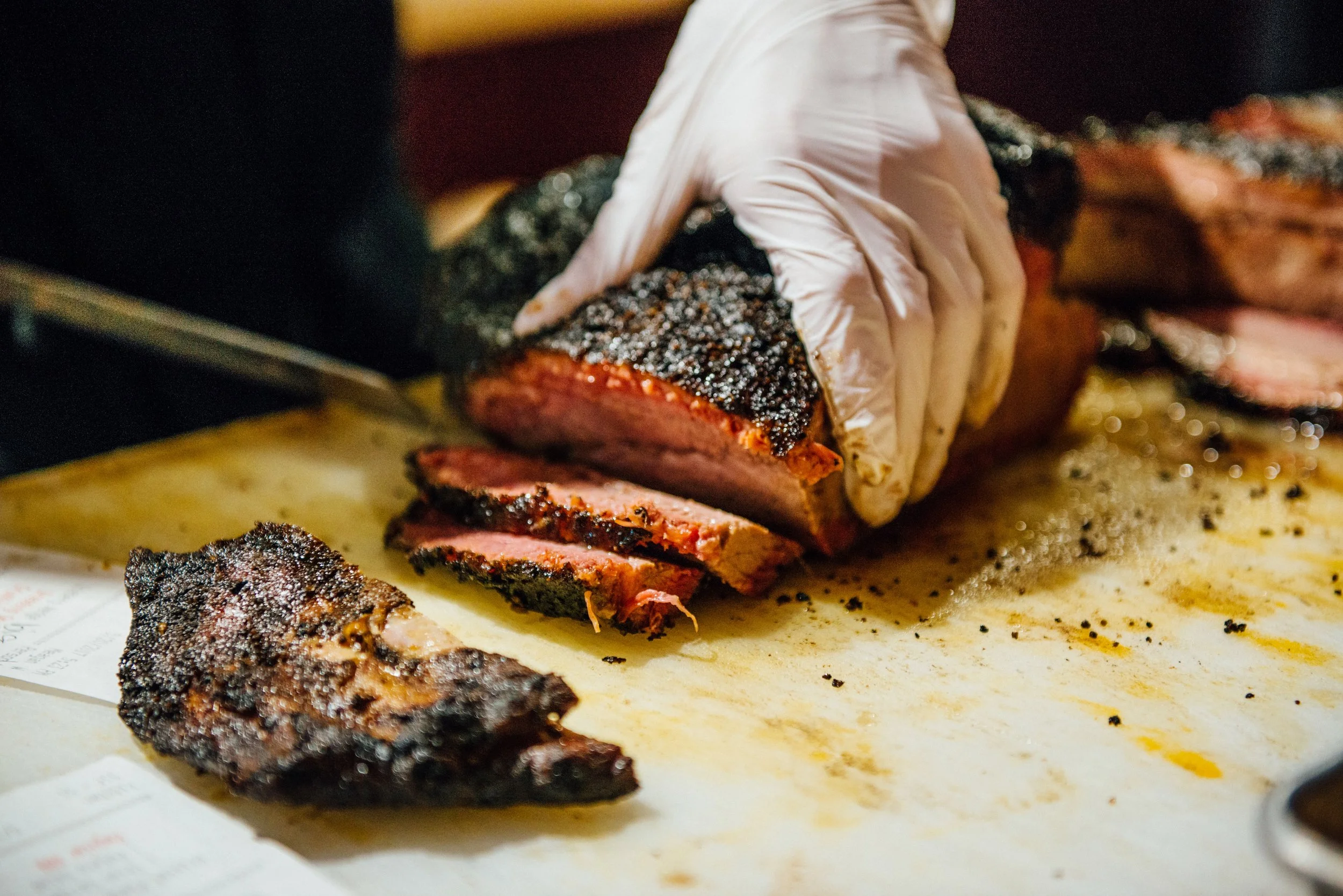 brisket on a wood cutting board being sliced for plating