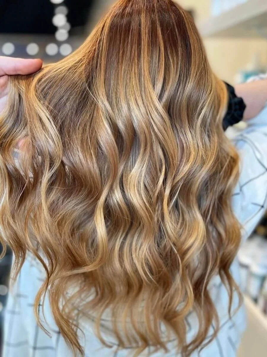 Close-up of long, wavy, golden blonde hair with lighter highlights.