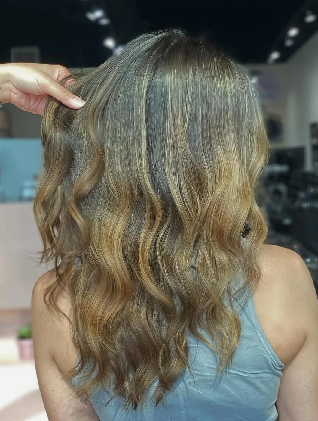Back view of a woman with medium-length, wavy blonde hair.