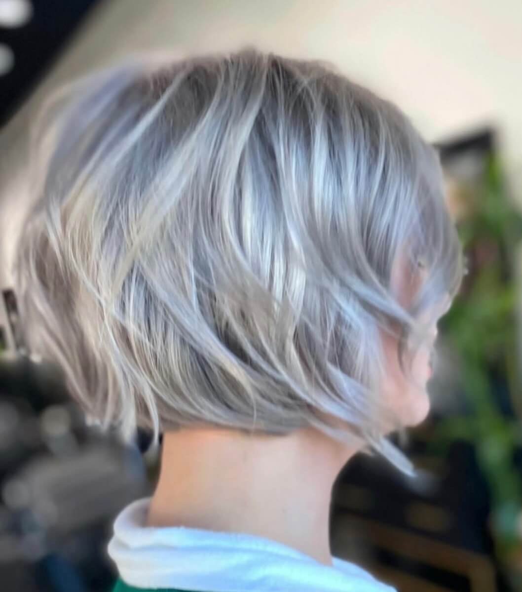 Side view of a person with short, wavy, silver-gray hair.