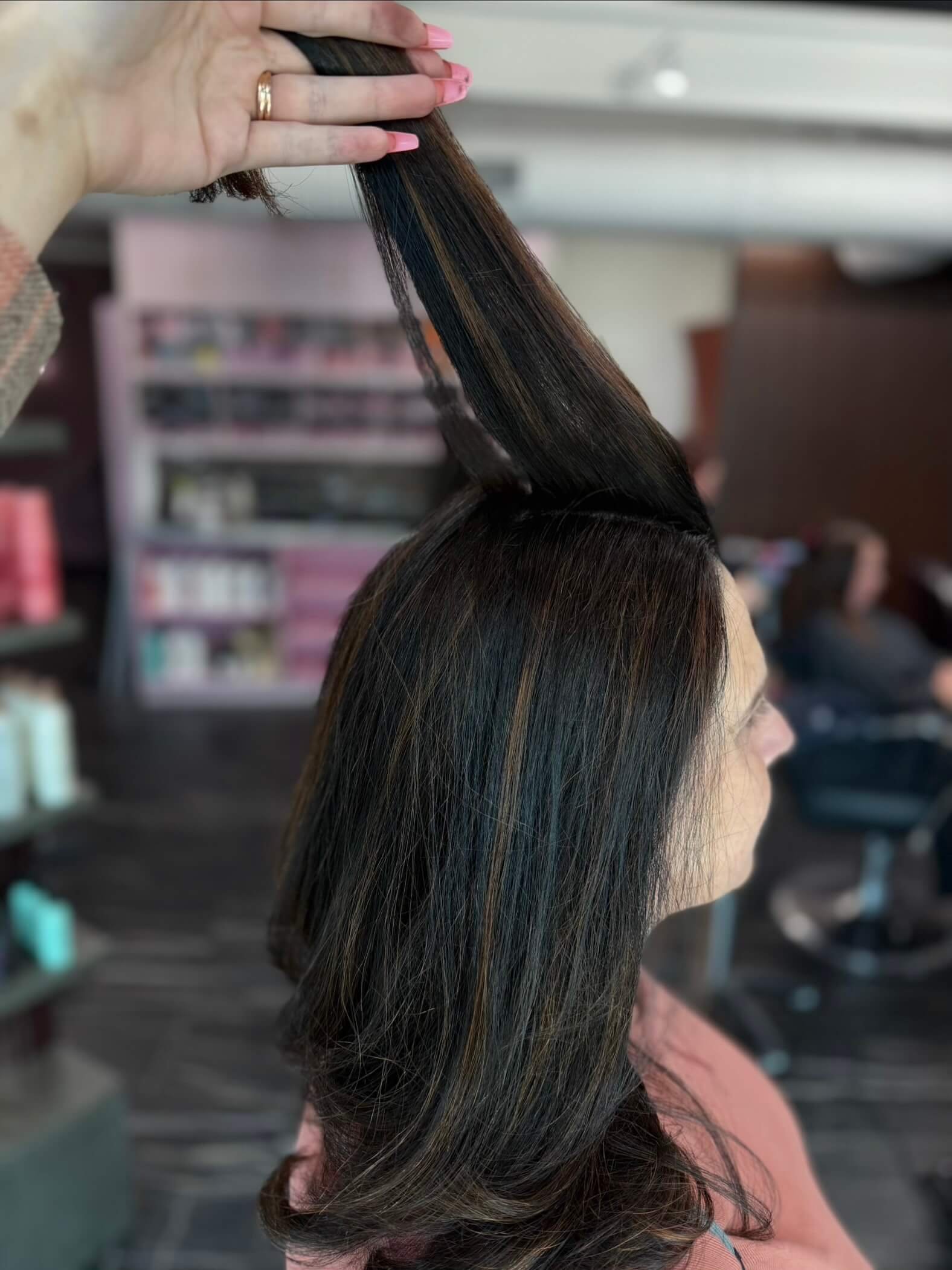 Back view of wavy, shoulder-length gray hair in a salon.