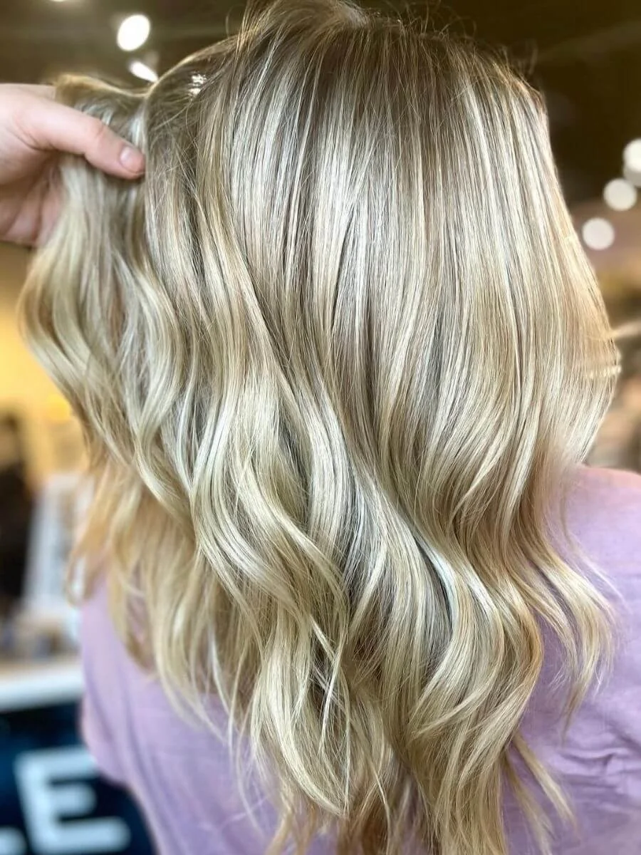 Close-up of a person's wavy, blonde hair in a salon setting.
