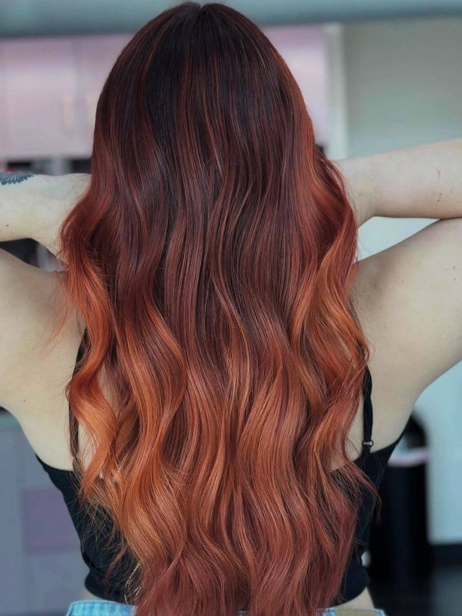 Back view of a woman with long wavy red hair.